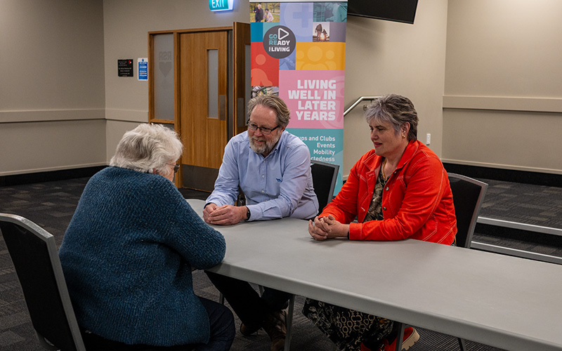 three adults talking around a table